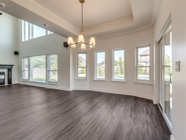 interior space with an inviting chandelier, ornamental molding, dark hardwood / wood-style flooring, and a raised ceiling