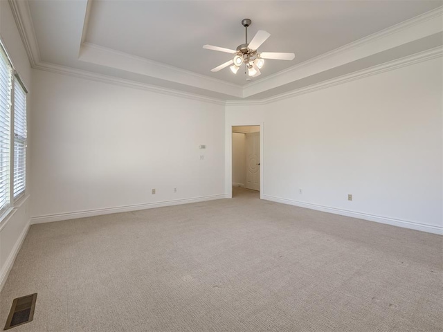 carpeted empty room featuring ceiling fan, ornamental molding, and a raised ceiling