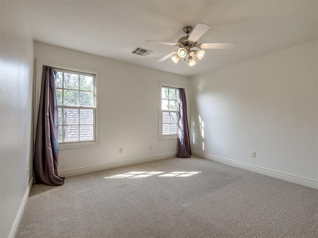 empty room with ceiling fan, plenty of natural light, and light carpet