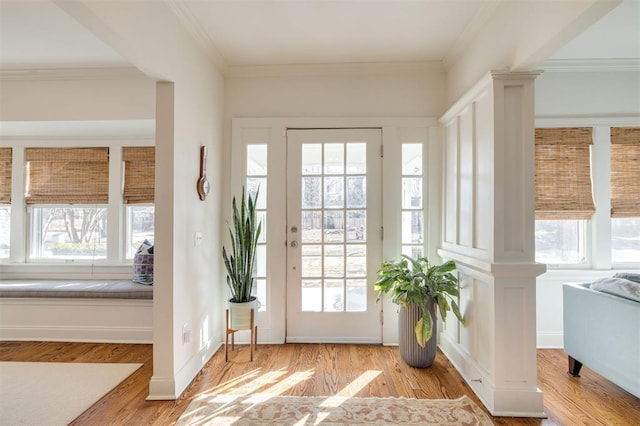 doorway with light hardwood / wood-style flooring, ornamental molding, and decorative columns