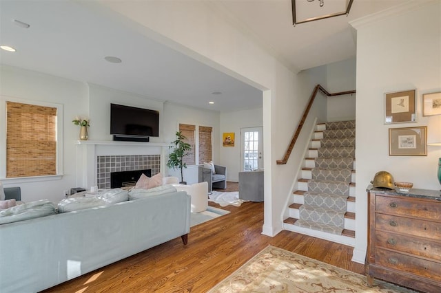 living room with ornamental molding, wood-type flooring, and a tile fireplace