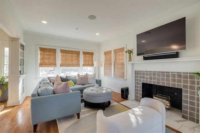 living room featuring crown molding, a healthy amount of sunlight, a fireplace, and light hardwood / wood-style floors