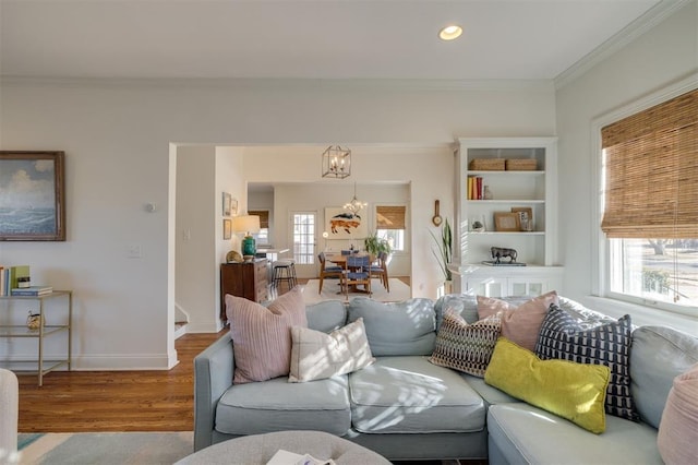 living room with a notable chandelier, plenty of natural light, ornamental molding, and wood-type flooring