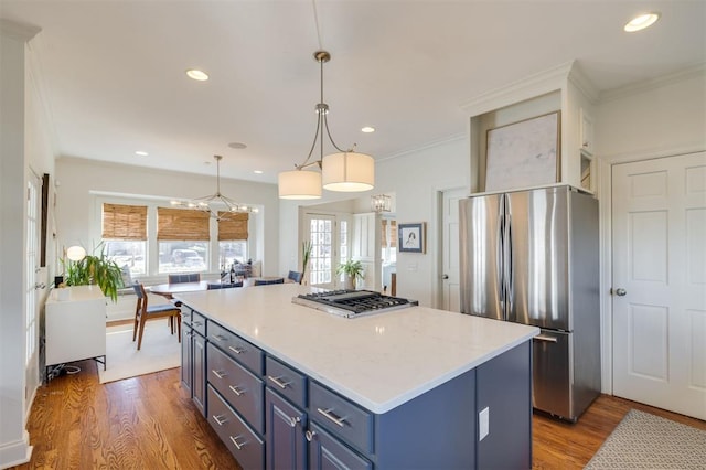 kitchen featuring a kitchen island, blue cabinets, hardwood / wood-style flooring, hanging light fixtures, and stainless steel appliances