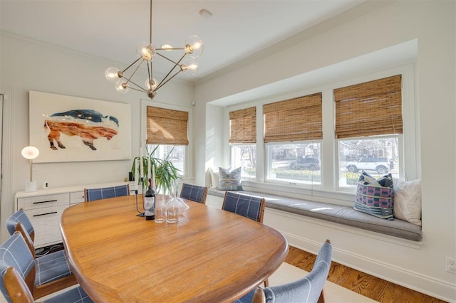 dining room with wood-type flooring, ornamental molding, a wealth of natural light, and an inviting chandelier