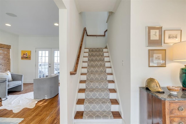 stairway featuring french doors, crown molding, and hardwood / wood-style floors