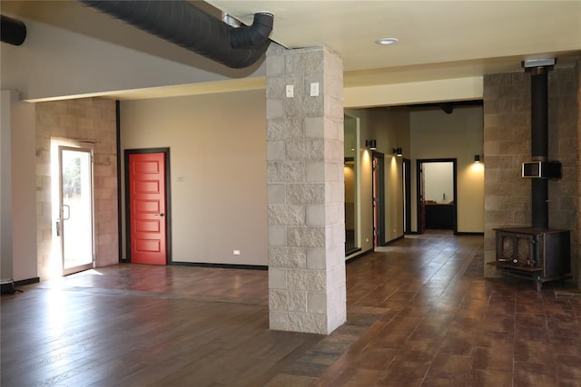 foyer entrance with baseboards, a wood stove, and dark wood-type flooring