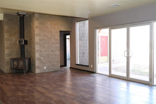 unfurnished living room with visible vents, wood finished floors, and a wood stove