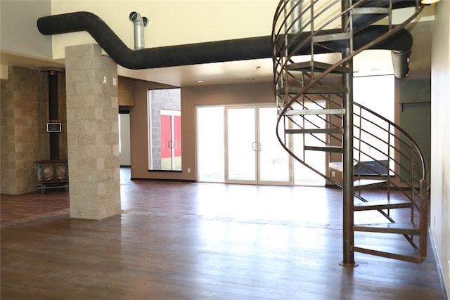 unfurnished living room with stairs, wood finished floors, and a wood stove