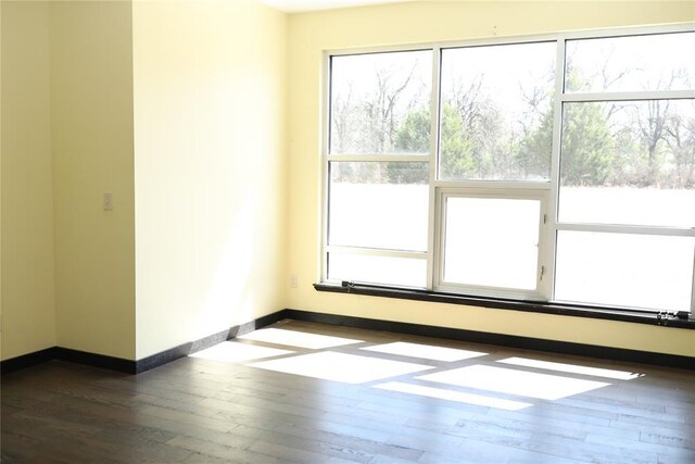 spare room featuring dark wood-style floors and baseboards
