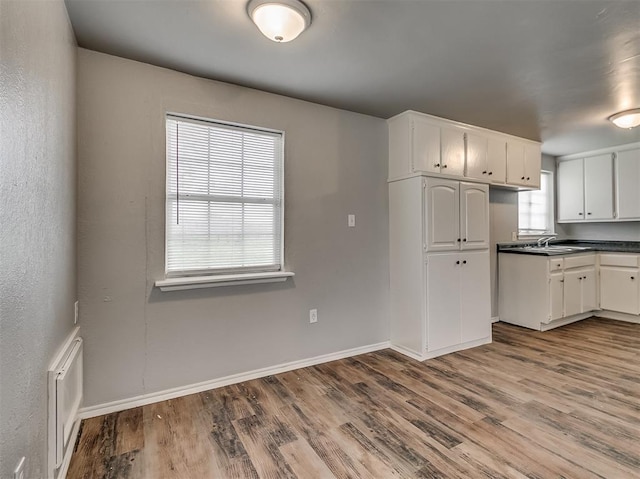 kitchen featuring wood-type flooring, sink, and white cabinets