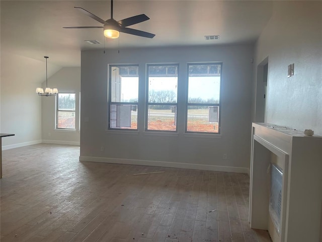 spare room with wood-type flooring and ceiling fan with notable chandelier