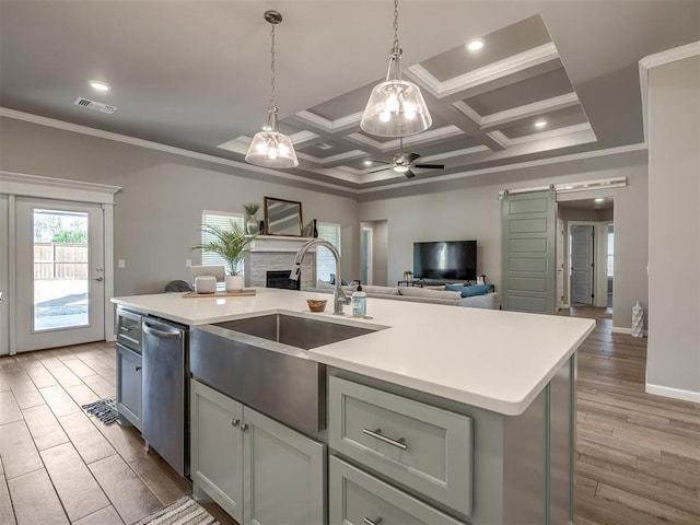 kitchen featuring sink, a center island with sink, stainless steel dishwasher, pendant lighting, and a barn door