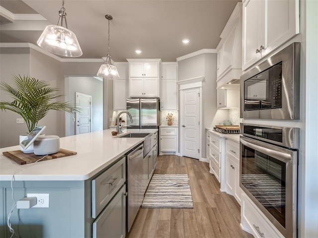 kitchen with decorative light fixtures, white cabinets, custom exhaust hood, stainless steel appliances, and a center island with sink