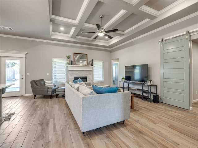 living room featuring ceiling fan, a barn door, light hardwood / wood-style floors, and a wealth of natural light