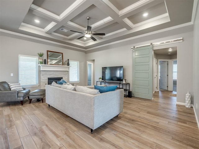 living room with ceiling fan, a barn door, plenty of natural light, and light wood-type flooring