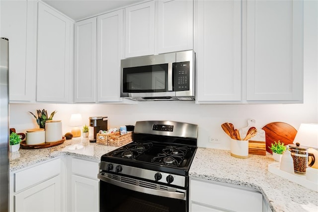 kitchen with white cabinetry, stainless steel appliances, and light stone counters