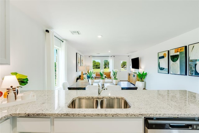 kitchen with light stone counters, sink, dishwasher, and white cabinets