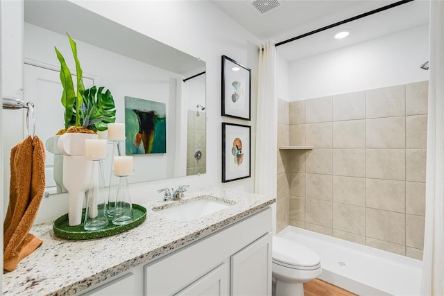 bathroom featuring tiled shower, vanity, and toilet