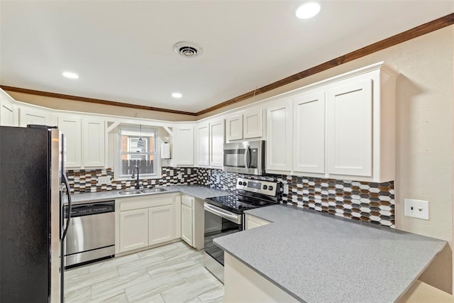 kitchen with sink, white cabinetry, stainless steel appliances, decorative backsplash, and kitchen peninsula