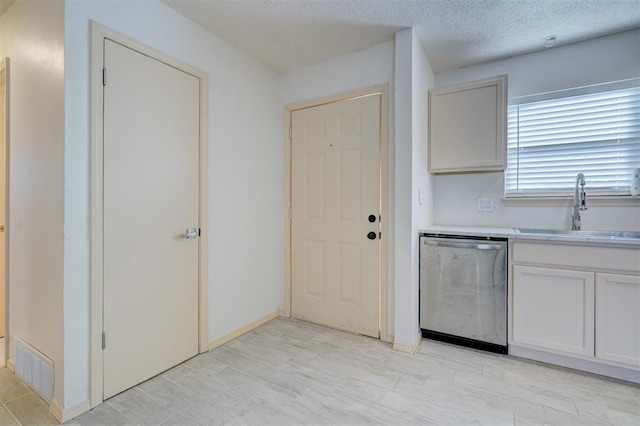 kitchen with sink, stainless steel dishwasher, white cabinets, and a textured ceiling