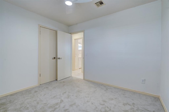 empty room featuring ceiling fan and light colored carpet