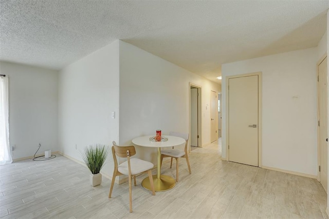 dining space with light hardwood / wood-style floors and a textured ceiling