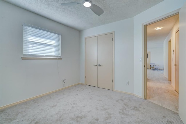 unfurnished bedroom with ceiling fan, light colored carpet, a closet, and a textured ceiling