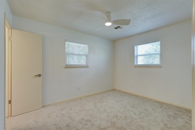 empty room with light colored carpet, a textured ceiling, and ceiling fan