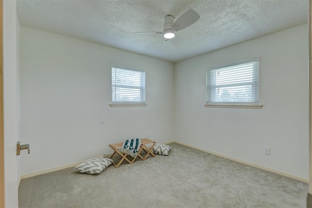 carpeted empty room with ceiling fan, plenty of natural light, and a textured ceiling