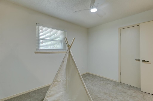 empty room featuring a textured ceiling, light colored carpet, and ceiling fan