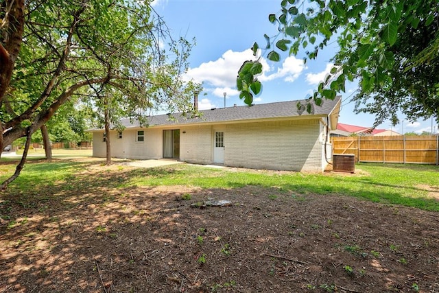 rear view of property with a lawn, a patio, and central air condition unit