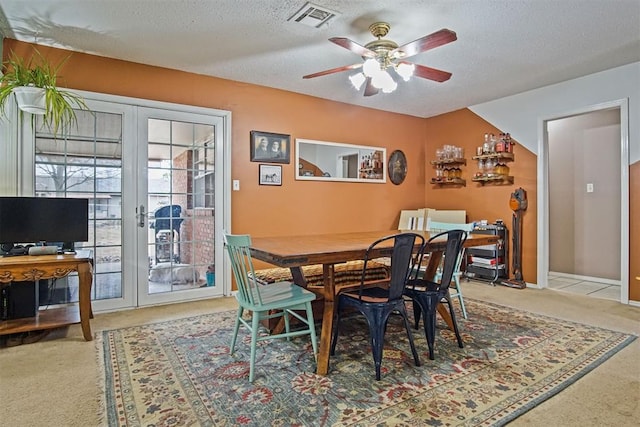 dining space with french doors, ceiling fan, carpet flooring, and a textured ceiling