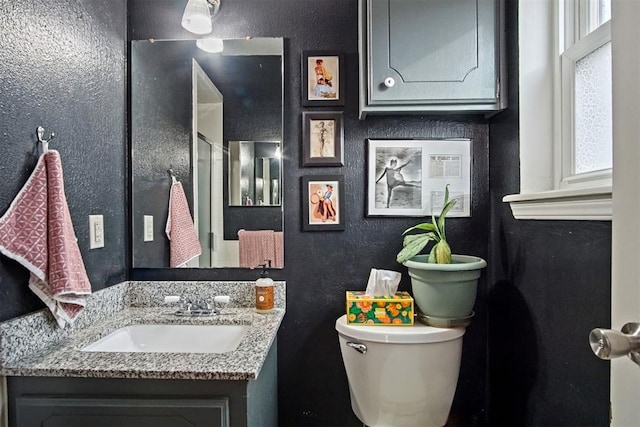 bathroom featuring a healthy amount of sunlight, toilet, and vanity