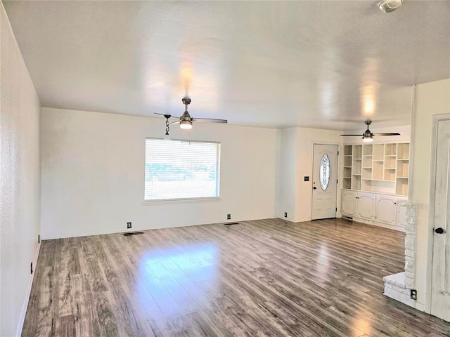 unfurnished living room with ceiling fan, hardwood / wood-style floors, and built in features