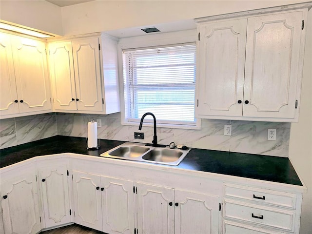 kitchen with sink, white cabinets, and backsplash