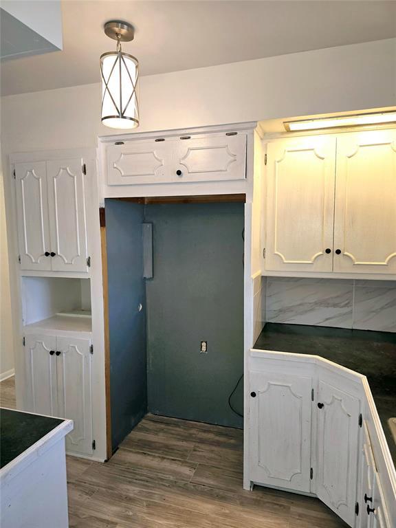 kitchen featuring hardwood / wood-style flooring, white cabinets, decorative light fixtures, and backsplash