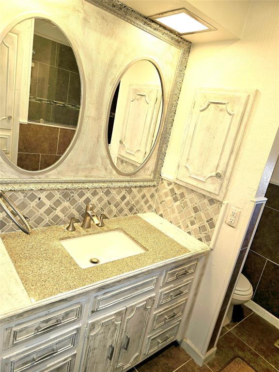 bathroom with tile patterned floors, toilet, tasteful backsplash, tile walls, and vanity