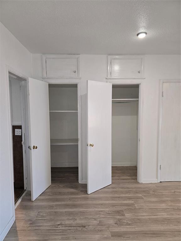 unfurnished bedroom with light wood-type flooring, a textured ceiling, and a closet