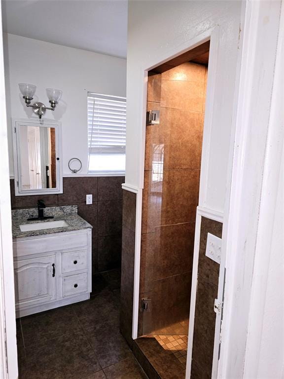 bathroom with vanity, tiled shower, tile walls, and tile patterned floors