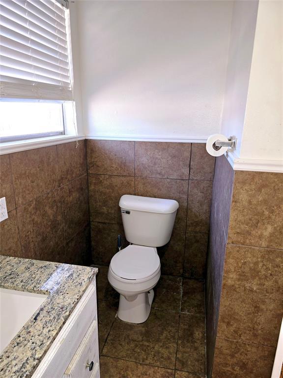 bathroom featuring vanity, toilet, and tile walls