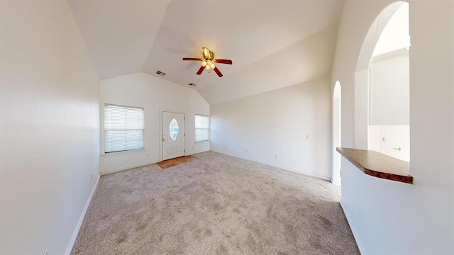 unfurnished living room with vaulted ceiling, light carpet, and ceiling fan