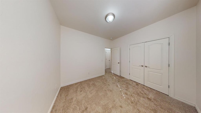 unfurnished bedroom with light carpet and a closet