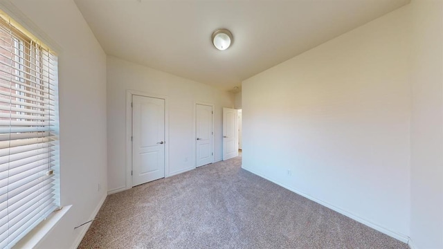 unfurnished bedroom featuring carpet floors and two closets