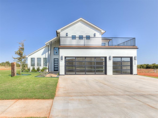 view of front facade featuring a garage, a balcony, and a front yard