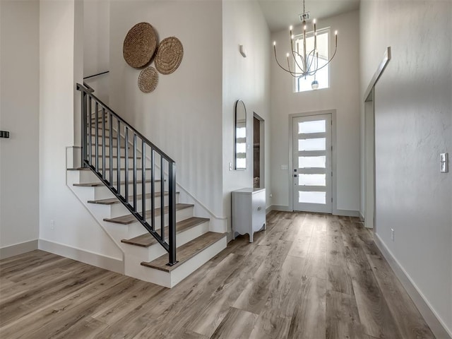 foyer with a high ceiling, hardwood / wood-style floors, and a chandelier