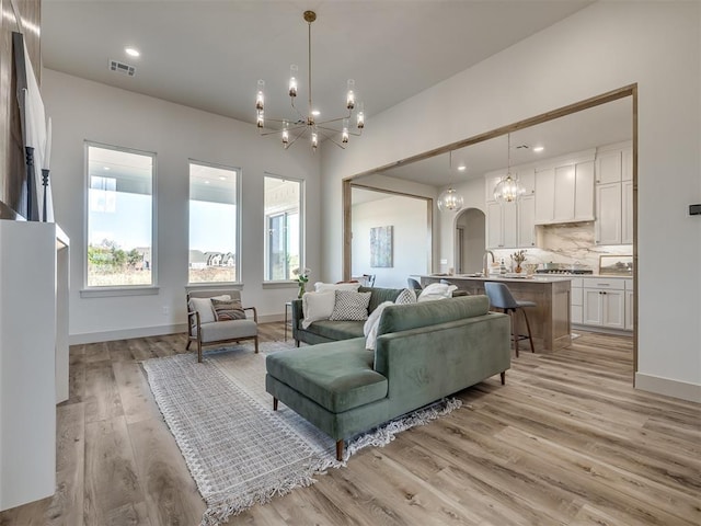 living room with sink, a chandelier, and light hardwood / wood-style floors