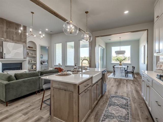 kitchen featuring white cabinetry, decorative light fixtures, a center island with sink, and built in shelves