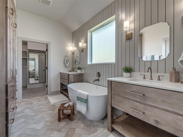 bathroom with vaulted ceiling, a washtub, and vanity