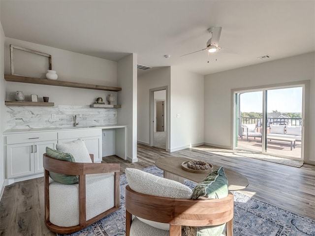 living room featuring hardwood / wood-style flooring, ceiling fan, and sink